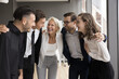 © fizkes - Motivation through support. Happy diverse businesspeople teammates stand in office close together engaged in teambuilding event with aged trainer coach hug shoulders feel strong bond team spirit unity