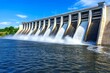 © Sanchai - A modern dam with towering concrete walls and high-pressure water jets spraying below