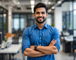 © Sajeduil - businessman, male office employee dressed in casual blue shirt posing for camera with arms crossed, standing alone at modern workplace. Management