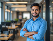© Sajeduil - businessman, male office employee dressed in casual blue shirt posing for camera with arms crossed, standing alone at modern workplace. Management