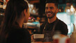 © Leah - Barista smiling while serving coffee to a customer in a cozy café setting