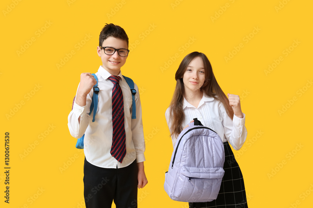 Cute schoolchildren showing winning gesture on yellow background