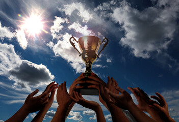 Wall Mural - man holding golden trophy and people reaching for it against sky