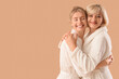 © Pixel-Shot - Happy young woman and her mother in bathrobes hugging on beige background