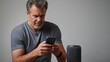 © Bonsales - Mature male configuring wireless smart speaker, connecting home technology with ease and exploring digital convenience through smartphone interaction