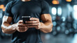 © Number One Studio - muscular man in black shirt is using smartphone in gym setting, showcasing strength and focus