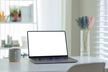 Fototapete - Comfortable workspace laptop with a blank screen, a coffee cup, and a decorative glass vase with  flowers.