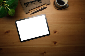 Poster - Top view office tablet with a blank white screen sits on a wooden desk, accompanied by a cup of coffee, a stylish pen, and a pair of glasses.