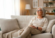 © Pier Fax - Senior Woman Relaxing on Cozy Sofa at Home, Enjoying Peaceful Moment