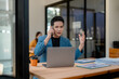 © PaeGAG - Asian businessman talking on phone and gesturing while working on laptop in office