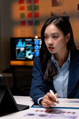 Aufkleber - Asian businesswoman analyzing financial charts and graphs on paperwork at night