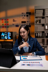Aufkleber - Asian businesswoman working late using tablet and analyzing financial statistics displayed on the screen