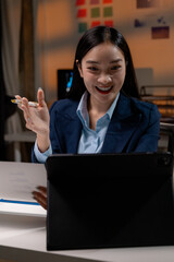 Poster - Asian businesswoman having video call on tablet in office at night