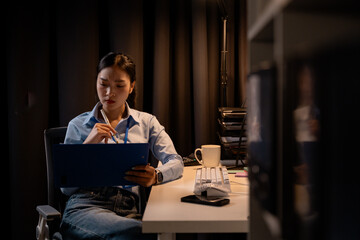 Aufkleber - Focused businesswoman working late at night in office holding clipboard and thinking