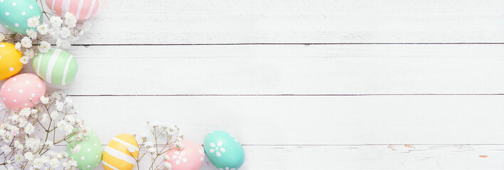 Aufkleber - Pastel Easter eggs and white spring flowers. Overhead view corner border against a white wood banner background. Copy space.