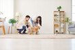 © Studio Romantic - Married couple spends time together at home training dog with toys. The pet owners engage in interactive activities with animal, strengthening bond and enjoying leisure time together.