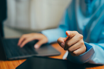 Poster - Business person pointing at camera while using laptop in modern office setting, Business concept.