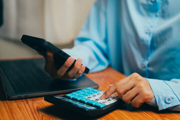 Poster - Person Using Calculator and Smartphone While Working at Laptop on Wooden Table, Business concept.