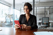 © Stock 4 You - Focused Latin Hispanic female businesswoman holding smartphone sitting at desk in office. Successful middle age business woman manager ceo using cell phone mobile pc for online working. Copy space
