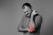 © Kateryna Muzhevska - Man has elbow problems after intense physical activity, long training or professional activity. warm-up and recovery after physical activity. Black and white photo, red elbow