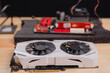 © Mdisk - High-Performance Graphics Card Close-Up, Close-up of dual-fan graphics card, its cooling system and hardware components with blurred motherboard and components on black foam in background
