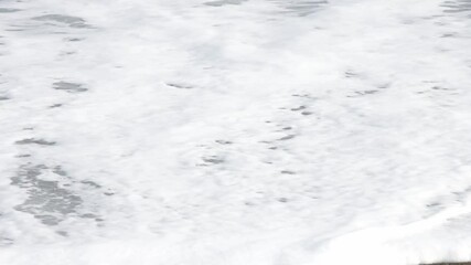 Wall Mural - soft white frothy wave flowing onto flat clean sandy beach