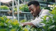 © Acronym - Man in a large industrial greenhouse with fresh natural plants. Concept of growing healthy food, diet, vegetarianism and technology. AI generated.