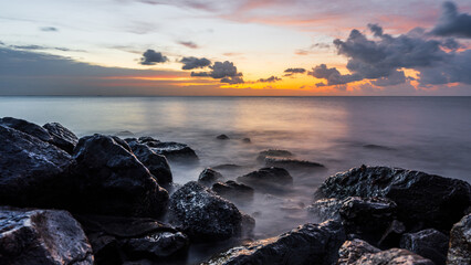 Wall Mural - landscape rock beach seaside in the evening with sunset sky over sea in golden hour, horizon sea dus