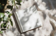 © Gustav - Elegant square magazine mockup on linen fabric with green leaves shadows, perfect for showcasing designs, presentations, or creative content in a natural light setting