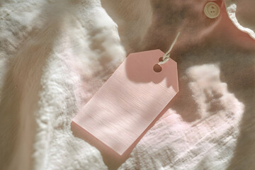 Poster - Macro Shot of Delicate Fabric with Button and Blank Pink Tag, Emphasizing Texture, Light, and Simple Elegance for Fashion or Retail Concepts