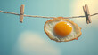 © Mirivox - Fried egg hanging on a clothesline with wooden clothespins against a blue sky background, symbolizing a quirky and playful concept of food in an unconventional setting.