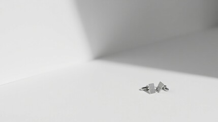 Poster - Elegant Silver Cufflinks Resting on a Pristine White Surface Illuminated by Soft Light