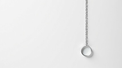 Poster - Simple silver chain with a circular pendant hanging against a plain white backdrop