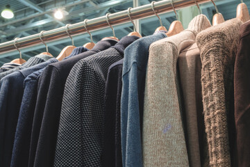 Poster - A rack of clothes with a blue jacket hanging on the left and a brown jacket hanging on the right