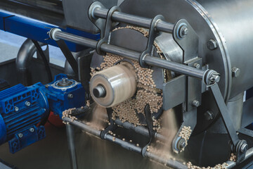 Poster - A machine is grinding up some material. The grinding process is in progress. The machine is made of metal and has a blue part