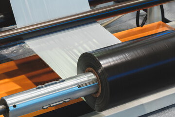 Poster - Automatic polyethylene plastic bag production machine with lighting effect. Close-up of the roller of the plastic bag production machine in the light blue scene. product packaging concept