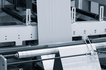 Poster - Automatic polyethylene plastic bag production machine with lighting effect. Close-up of the roller of the plastic bag production machine in the light blue scene. product packaging concept