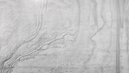 Poster - A grey and white wall with a pattern that resembles a wave. The wall appears to be made of concrete and has a textured surface