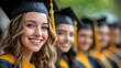 © Nattapol - Smiling graduate in cap and gown with classmates behind her.