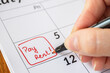 © AFilipczuk - Rent Payment Due Date In Calendar. Close up of pay rent written on date with red marker.