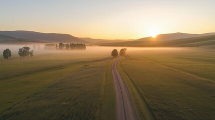 Aufkleber - A misty road disappearing into a vast open field at sunrise