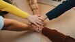 © InfiniteFlow - A diverse group of individuals showcases teamwork by placing their hands together in a gesture of support during a collaborative meeting on a wooden table. SACTR