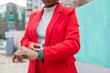 © ADDICTIVE STOCK - Confident woman in a red suit checks smartwatch outdoors