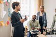 © Maskot - Young male entrepreneur discussing with colleagues while standing near whiteboard in meeting room at office