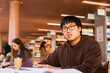 © Maskot - Thoughtful young male university student with books sitting at library desk