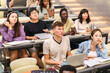 © Maskot - High angle view of multiracial male and female students sitting in lecture hall at college
