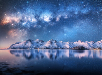 Wall Mural - milky way over snowy mountains and fjord at winter night. panoramic landscape with snowy rocks, blue