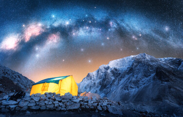 Wall Mural - milky way acrh over glowing yellow tent in the snowy mountains at starry night. hiking and trekking 
