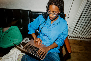 High angle view of female entrepreneur using laptop while sitting on sofa at office