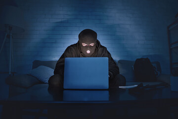 Fototapete - Private Information Security Concept. Masked hacker using pc, sitting in the dark on couch, stealing big data